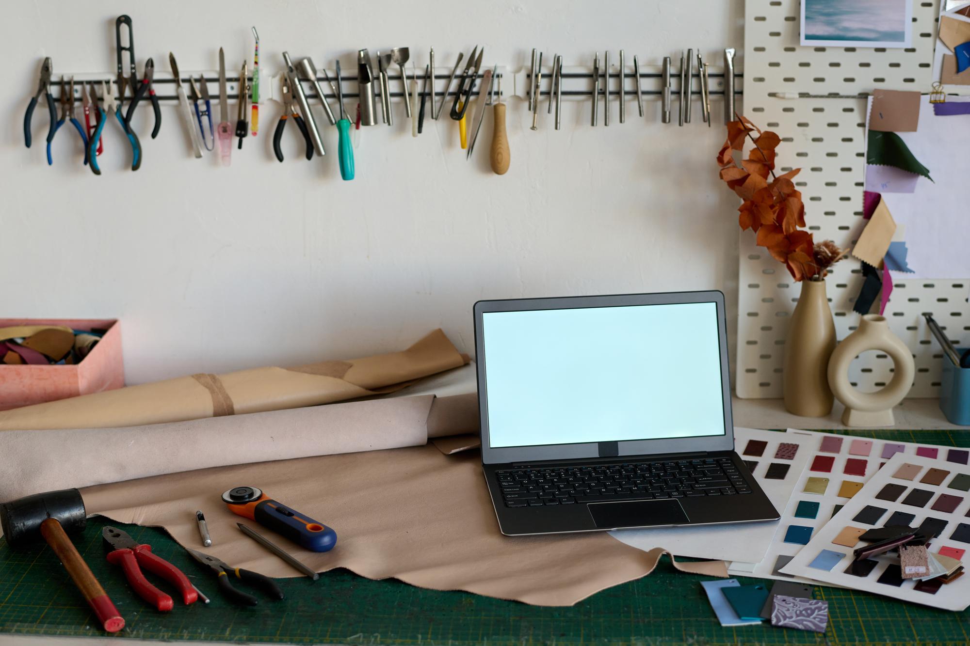 atelier digitale con attrezzi di ricamo e laptop